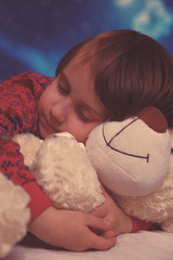 Little cute child girl hugs the teddy bear and sleeps on bed in her bedroom, happy little girl, family home concept.happy carefree childhood. Retro styled.