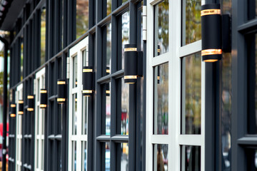 Obraz premium Close-up of a dark facade with white windows and black modern decorative lanterns, the exterior of the restaurant.