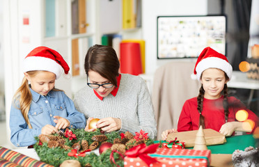 Young woman with decorative toy ball and her little daughters preparing for Christmas