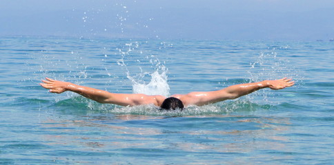 Muscular young man swimming butterfly stiles