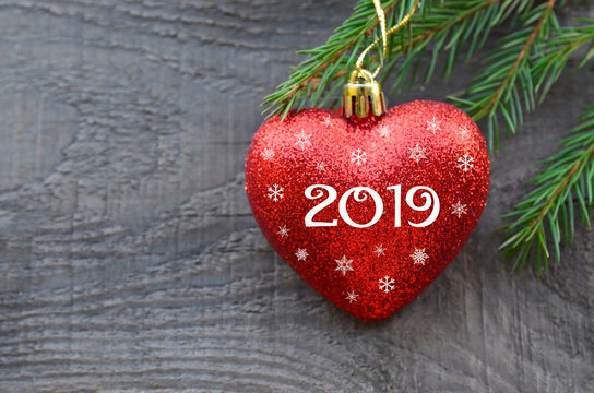 2019 New Year greeting card with red Christmas heart and fir tree branch on old wooden background.Winter holidays festive decoration with copy space.Selective focus.