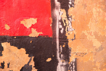 Abstract background of old painted wall. Peeling old red, brown and yellow paint on a vertical wall.