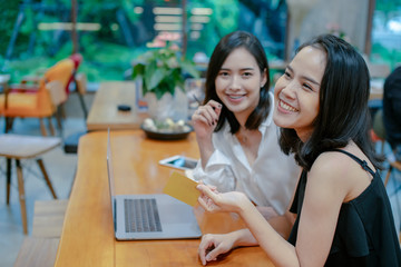 Two excited friends buying online with credit card and a laptop,Social media and Online shopping concept.