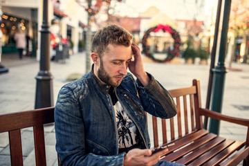 Young worried man chatting on the phone and waiting for a friend to call