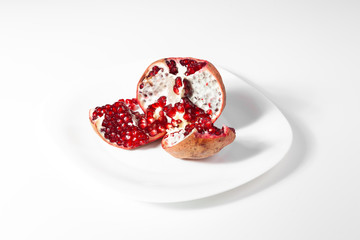 Broken pomegranate lies on a white plate.