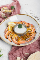 A dozen baked tiger shrimps in a plate with sauceboat