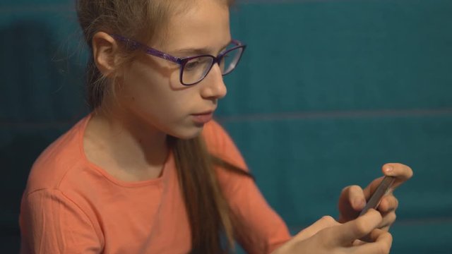 Young girl plays in a gadget with emotions at home

