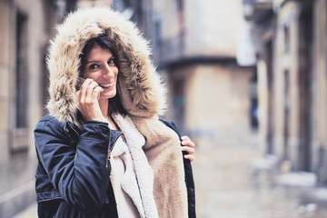 Mujer joven hablando por teléfono en un día de invierno lluvioso