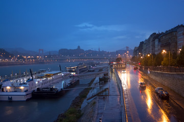 Fototapeta na wymiar Wet riverfront highway against old city skyline. Rainy night. Budapest