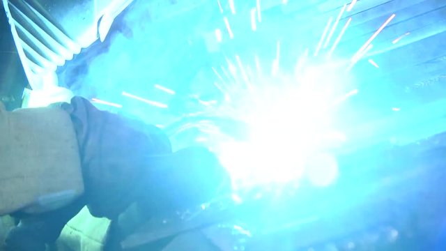Welding with sparks by Process fluxed cored arc welding. Industrial welder welding fabricated construction in factory, Welding process by Shielded Metal Arc Welding (SMAW) or Stick Welding.