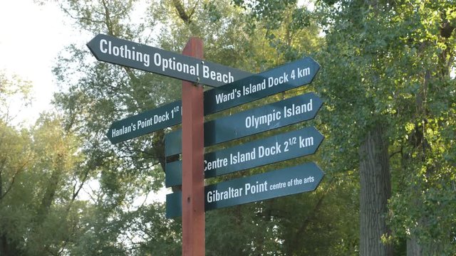Toronto Islands sign including directions to clothing optional nude beach. Handheld shot with stabilized camera.