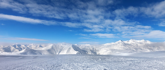 Ski slope, snow mountains and blue sky with clouds