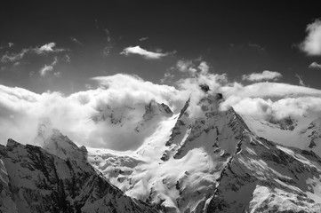 Beautiful high mountains in snow and sunlight sky with clouds at cold winter day