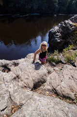 Blonde female hiker stands on a bluff cliff at Interstate State Park in Minnesota along the St. Croix River