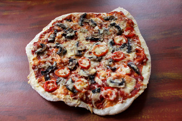 tasty pizza with mushrooms, tomatoes and cheese on brown