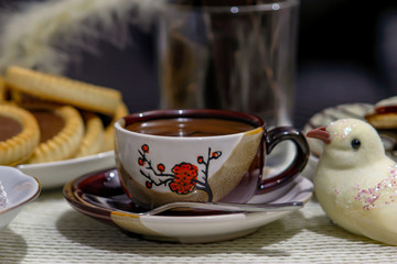Small cup of hot turkish coffee with cookies on table. Turkish coffee or arabic coffee or greek coffee, pastries and figurines of birds.