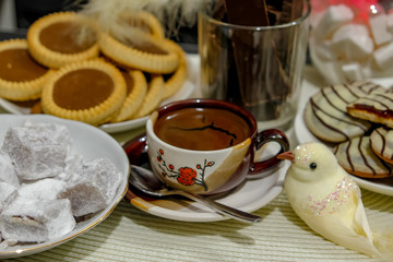 Small cup of hot turkish coffee with cookies on table. Turkish coffee or arabic coffee or greek coffee, pastries and figurines of birds.