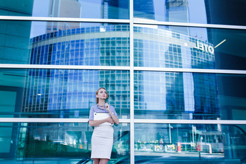 Portrait of business woman with laptop in her hands standing next to the office building.