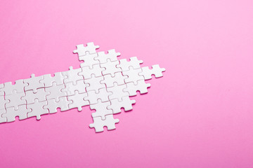 White puzzle. Arrow shape puzzle on pink background. Top view - obrazy, fototapety, plakaty