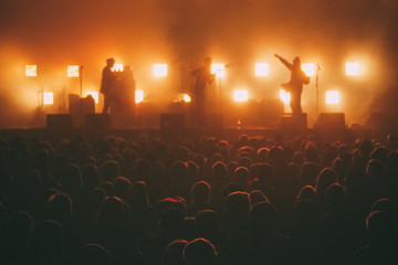  Crowd of big music festival with rock band silhouette on a stage in a backlights at the background