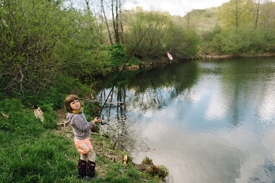 Young girl holding a fishing pole with bait hooked onto it