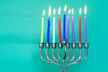 Image of jewish holiday Hanukkah on happy green background with menorah (traditional candelabra) and burning candles.