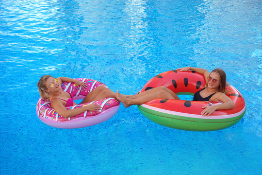 girls smiling smimming in pool on the inflatable mattress