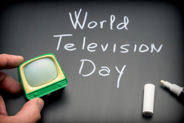 World Television Day written on Blackboard next to miniature TV, conceptual image