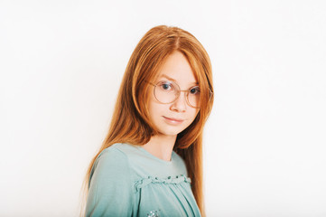 Studio shot of young preteen red-haired girl against white background, wearing eyeglasses