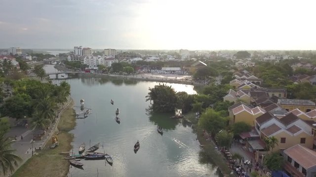 2K Aerial view of the river with some tour boats on water in ancient Hoi An, Vietnam. Hoian city beautiful aerial panorama at sunset