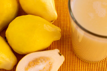 Fresh guava smoothie or juice in glass, ripe guava fruit and cut half on yellow tablecloth background.