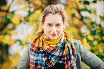 Outdoor autumn portrait of beautiful woman wearing colorful scarf