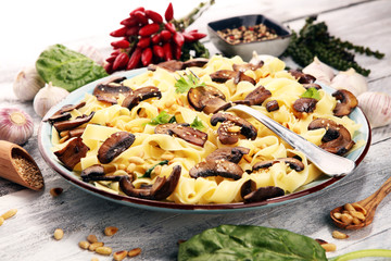 Pasta fettuccine with mushrooms and spinach on rustic background.
