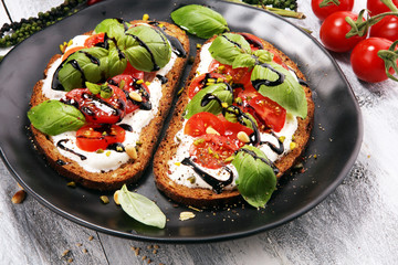 Bread with cream cheese and tomato for lunch table. Sharing antipasti on party or summer picnic time over wooden rustic background