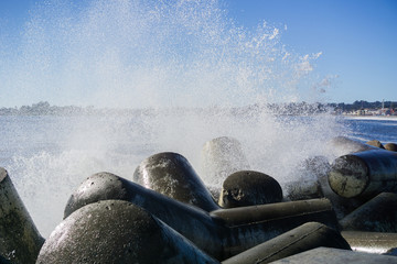 Waves breaking on the concrete blocks protecting the jetty of Santa Cruz Harbor, California