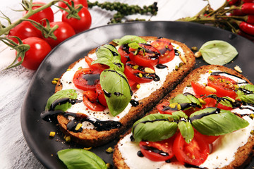 Bread with cream cheese and tomato for lunch table. Sharing antipasti on party or summer picnic time over wooden rustic background
