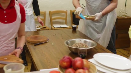 Diverse group of cooking class students in aprons and gloves are making meals together in kitchen. Food preparing - Powered by Adobe