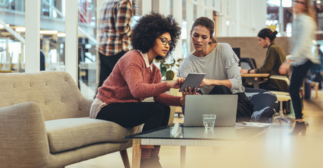 Female coworkers discussing work in office - Powered by Adobe