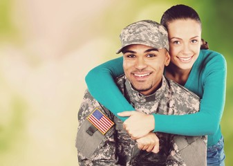 Smiling soldier with his wife standing against nature background