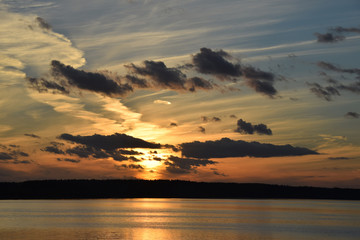 Fototapeta premium evening sunset on the river sea bright light reflection water clouds sky