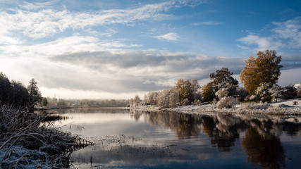 cold and calm morning view by the lake with first snow in winter