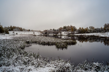 cold and calm morning view by the lake with first snow in winter