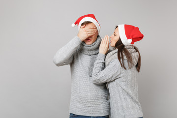 Merry fun couple girl guy in red Santa Christmas hat gray sweaters scarves isolated on grey wall...
