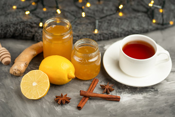 Lemon and ginger jam with toast and spices, with a cup of tea on a dark background