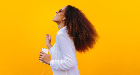 African girl having fun listening music on smartphone
