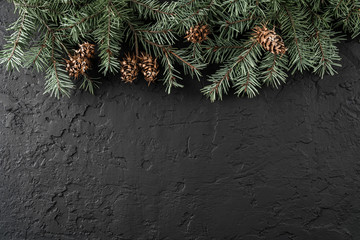 Christmas fir branches and pine cones on dark background with snowflakes. Xmas and New Year theme. Flat lay, top view, space for text, wide composition