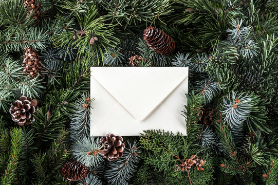 Christmas letter envelope on fir branches background with pine cones. Xmas and New Year theme. Flat lay, top view