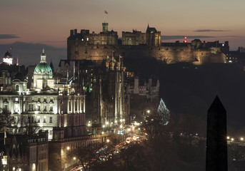 Fototapeta premium View of Edinburgh's Castle at dusk from Calton Hill, with lights on and Christmas tree in the street. Edinburgh, Scotland.
