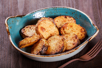 Grilled potatoes in the plate on wooden background. Top view