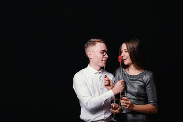 Elegant smiling couple with glasses of champagne in studio on a black background